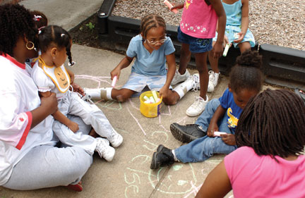 Mother sitting with kids playing on the sidewalk